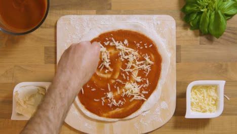 Top-View-Male-Sprinkling-Grated-Cheese-on-Pizza