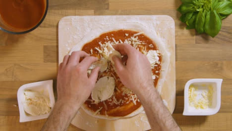 Top-View-Male-Placing-Mozzarella-on-Pizza