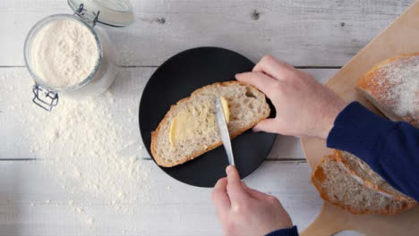 Ansicht-Von-Oben-Hand-Buttern-Scheibe-Brot