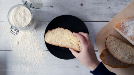 Top-View-Hand-Taking-Slice-of-Buttered-Bread-from-Plate