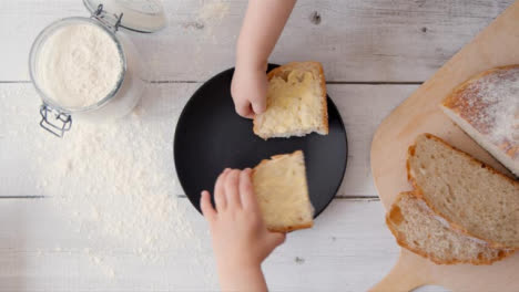 Two-View-Two-Kids-Take-a-Slice-of-Bread-from-Plate