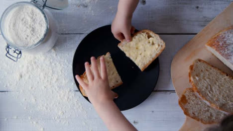 Zwei-Ansichtskinder-Nehmen-Eine-Scheibe-Brot-Vom-Teller