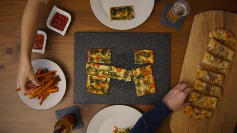 Top-View-Couple-Eating-Pizza-Meal-at-Table