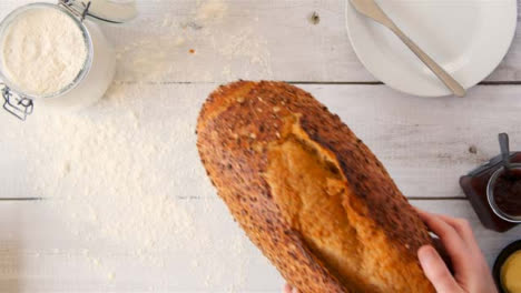 Top-View-Hand-Puts-Down-Seeded-Bread-on-Table