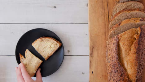 Top-View-Hand-Takes-Slice-of-Buttered-Seeded-Bread-from-Plate