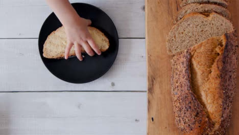 Top-View-Child-Picking-Up-Buttered-Slice-of-Bread