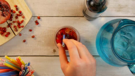 Top-View-Male-Hands-Adding-Pomegranate-Seeds-to-Drink-and-Stirring
