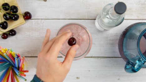 Top-View-Male-Hand-Adding-Cherry-to-Drink-and-Sliding-It-Forward