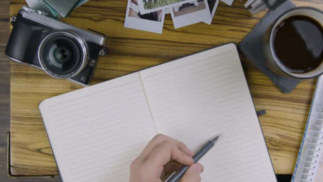 Man-Tapping-His-Pen-On-Blank-Notebook-Page-On-Coffee-Table