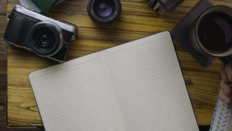 Man-Sipping-Coffee-and-Turning-Page-In-His-Notebook-On-Coffee-Table