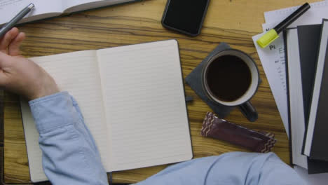 Man-Leaning-On-Notebook-and-Reading-from-Textbook-