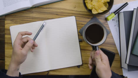 Man-Drinking-Coffee-and-Holding-Pen-In-Other-Hand