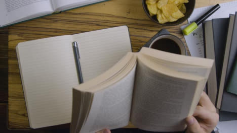 Man-Reading-Book-Whilst-Sat-at-Table-with-More-Textbooks