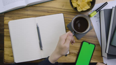 Man-Placing-Coffee-Down-and-Scrolling-On-Smart-Teléfono-with-Green-Screen