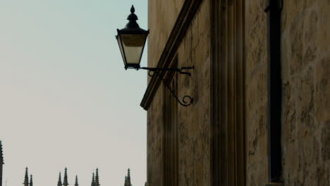 Rising-Shot-of-Old-Wall-Mounted-Light-On-University-of-Oxford-Grounds