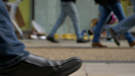 Defocused-Long-Shot-of-Feet-Walking-Past-Homeless-Persons-Belongings-In-Doorway-01