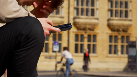 Close-Up-Shot-of-Man-Looking-at-Phone-On-Old-Street-In-Oxford-02