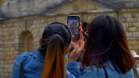 Over-the-Shoulder-Shot-of-Two-Friends-Taking-Photo-of-Radcliffe-Camera-Building