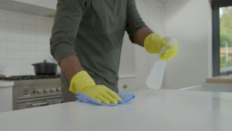 Man-Cleaning-Kitchen-Work-Surface-with-Rubber-Gloves-and-Disinfectant