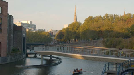 Wide-Shot-of-Rowing-Boat-Travelling-Under-Castle-Bridge-In-Bristol-