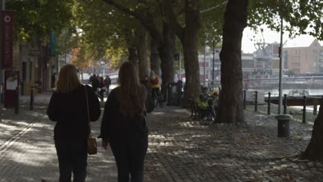 Tracking-Shot-of-Two-Women-Walking-Along-Waterside-Path-In-Bristol-England