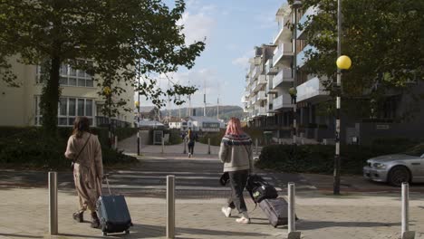 Wide-Shot-of-Two-People-with-Suitcases-Walking-Across-Street-In-Bristol-England