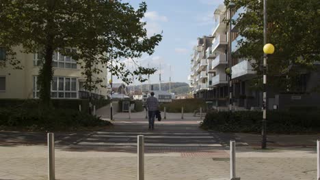 Wide-Shot-of-Man-Walking-Across-Zebra-Crossing-In-Bristol-England