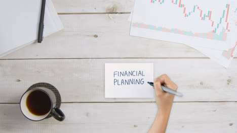 Top-Down-View-of-Woman-Writing-Financial-Planning-On-Paper-with-Business-Documents