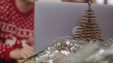 Extreme-Nahaufnahme-Von-Weihnachtlichen-Tischdekorationen-Vor-Dem-Paar-Mit-Einem-Laptop