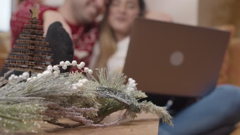 Extreme-Nahaufnahme-Von-Weihnachtsschmuck-Als-Paar-Im-Hintergrund-Interagieren-Mit-Laptop