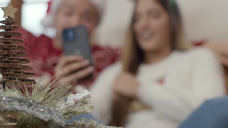 Extreme-Close-Up-of-Christmas-Decorations-As-Couple-In-Background-Interact-with-Teléfono