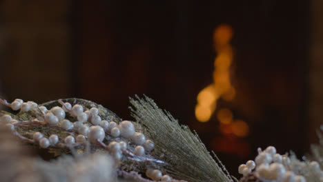 Extreme-Close-Up-Shot-of-Table-Christmas-Decorations-In-Front-of-Cosy-Fireplace