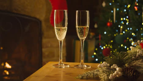 Nahaufnahme-Von-Zwei-Gläsern-Champagner-Auf-Dem-Tisch-Vor-Dem-Kamin