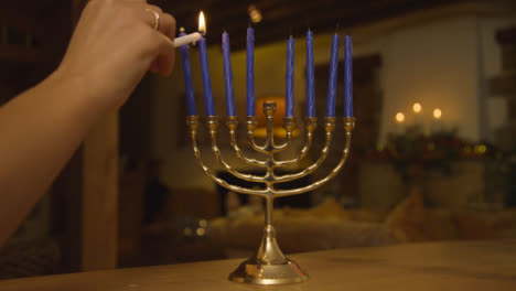 Close-Up-Shot-of-Female-Hand-Lighting-Candles-On-Menorah-During-Hanukkah