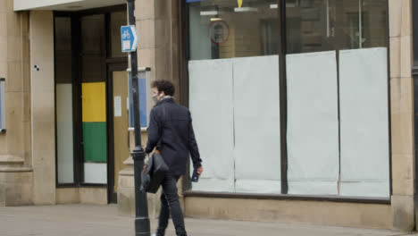 Long-Shot-of-Man-Walking-Past-Closed-Down-Shop-In-Oxford-England