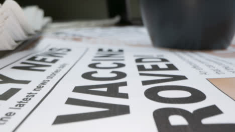 Sliding-Extreme-Close-Up-of-Pile-of-Newspapers-Front-Pages-with-Headlines-On-Covid-19-Vaccines
