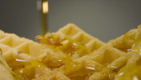 Sliding-Extreme-Close-Up-Shot-of-Maple-Syrup-Pouring-Onto-Waffles