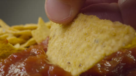 Sliding-Extreme-Close-Up-Shot-of-Nachos-Being-Dipped-Into-Spicy-Sauce-