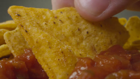 Sliding-Extreme-Close-Up-Shot-of-Some-Nachos-Being-Dipped-Into-Spicy-Sauce-
