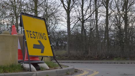 Close-Up-of-Cars-Driving-Past-COVID-19-Testing-Site-Road-Sign
