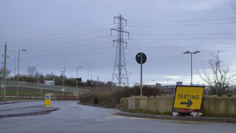 Wide-Shot-of-Car-and-Lorry-Passing-COVID-Testing-Site-Road-Sign