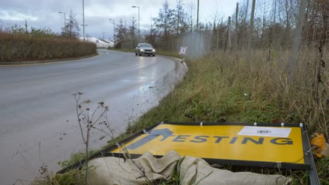 Weitwinkelaufnahme-Des-Vorbeifahrenden-Autos,-Das-über-Das-Straßenschild-Des-Covid-19-Testgeländes-Gefallen-Ist