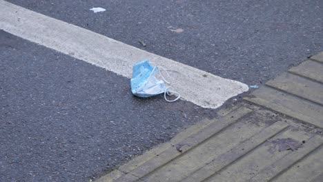 Handheld-High-Angle-Shot-of-Pedestrian-Walking-Over-Discarded-Face-Mask