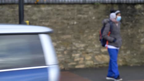 Defocused-Wide-Shot-of-Person-Wearing-Face-Mask-Crossing-Road