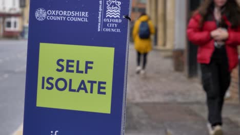 Handheld-Close-Up-Shot-of-Self-Isolate-Signage-In-Oxford-City-Centre