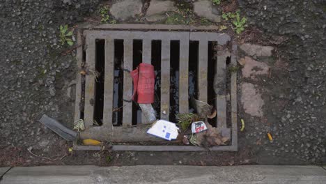 Handheld-High-Angle-Shot-Looking-Down-at-Discarded-Face-Mask-In-Drain-
