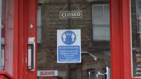 Handheld-Medium-Shot-of-Social-Distancing-Sign-In-a-Shop-Window