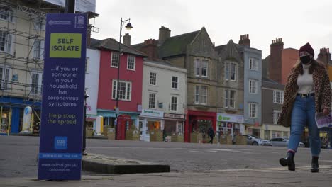 A-Wide-shot-of-Person-Walking-Past-NHS-Self-Isolate-Sign-In-Oxford