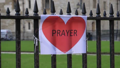 Handheld-Close-Up-Shot-of-A4-Prayer-Sign-Tied-to-Railing-