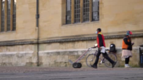 Defocused-Shot-of-Delivery-Driver-Walking-Past-Cyclist-In-Oxford